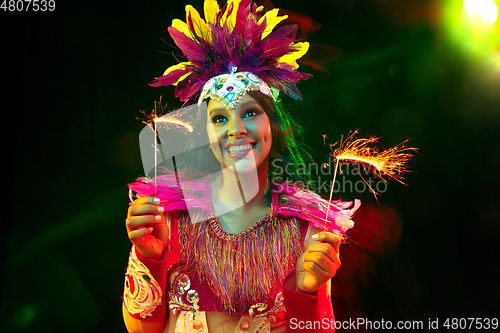 Image of Beautiful young woman in carnival mask and masquerade costume in colorful lights