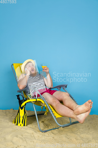 Image of Happy young man resting on blue studio background