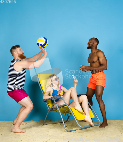Image of Happy young friends resting on blue studio background