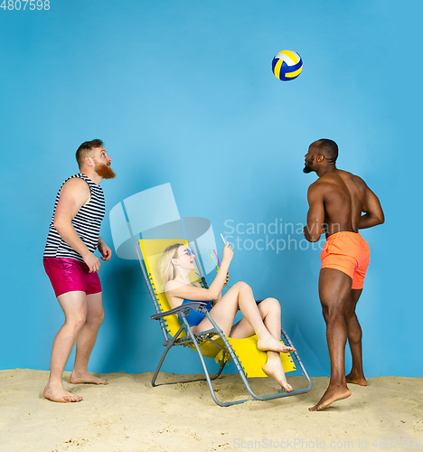 Image of Happy young friends resting on blue studio background
