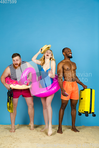 Image of Happy young friends resting on blue studio background