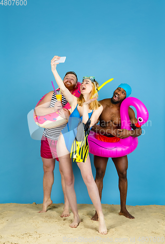 Image of Happy young friends resting on blue studio background