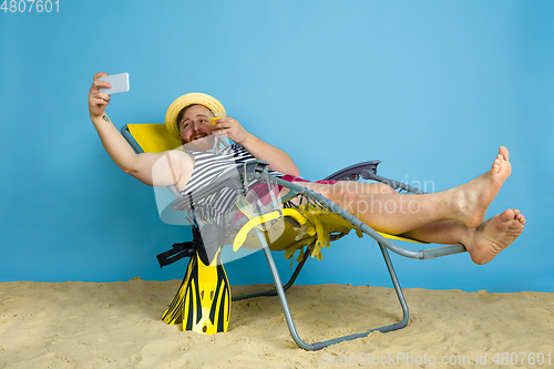 Image of Happy young man resting on blue studio background