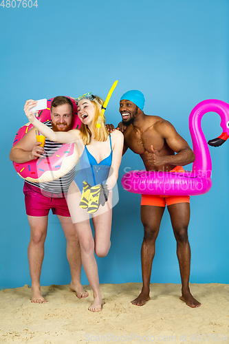 Image of Happy young friends resting on blue studio background