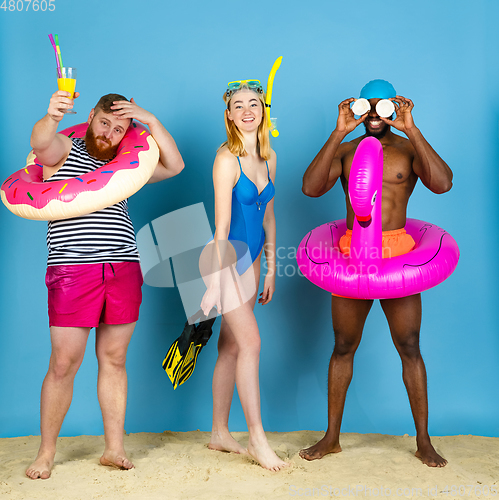 Image of Happy young friends resting on blue studio background
