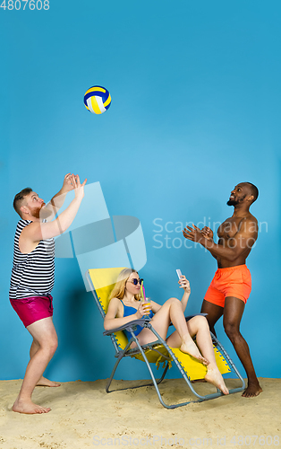 Image of Happy young friends resting on blue studio background