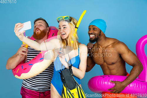 Image of Happy young friends resting on blue studio background