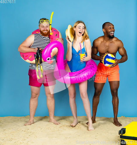 Image of Happy young friends resting on blue studio background