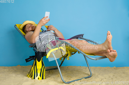 Image of Happy young man resting on blue studio background