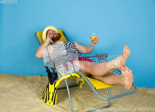 Image of Happy young man resting on blue studio background