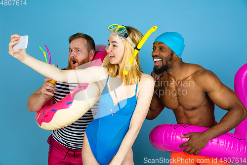 Image of Happy young friends resting on blue studio background