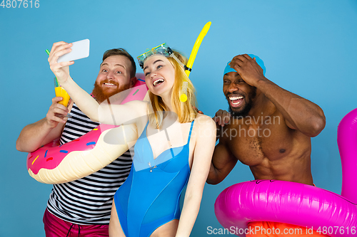 Image of Happy young friends resting on blue studio background