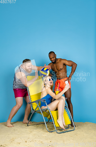 Image of Happy young friends resting on blue studio background