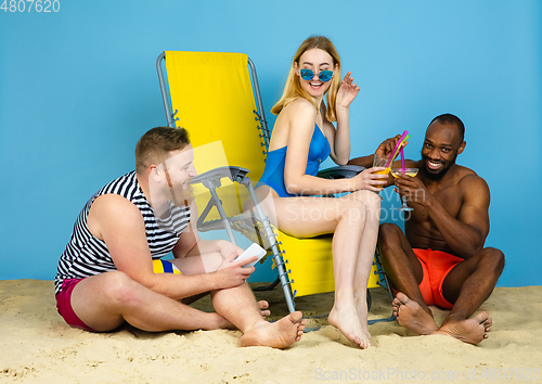 Image of Happy young friends resting on blue studio background