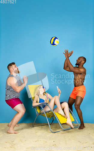Image of Happy young friends resting on blue studio background