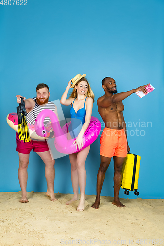 Image of Happy young friends resting on blue studio background