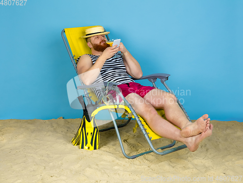 Image of Happy young man resting on blue studio background