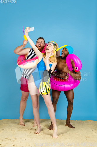 Image of Happy young friends resting on blue studio background