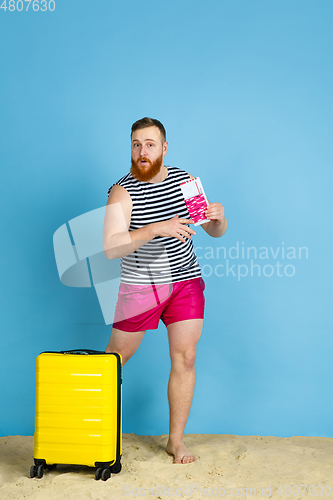 Image of Happy young man resting on blue studio background