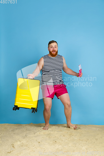 Image of Happy young man resting on blue studio background