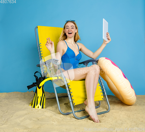 Image of Happy young woman resting on blue studio background