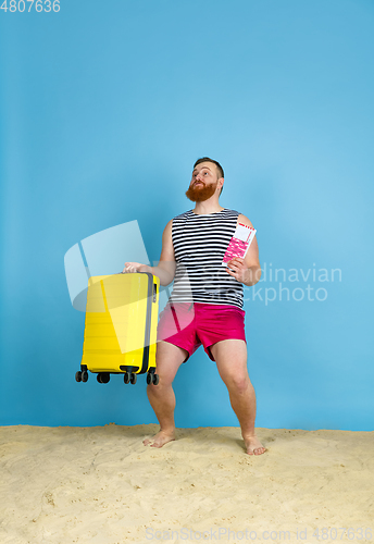 Image of Happy young man resting on blue studio background