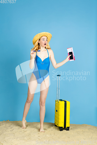 Image of Happy young woman resting on blue studio background