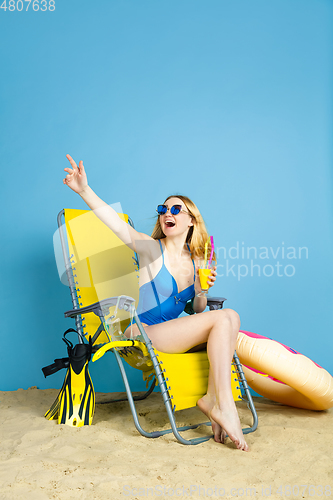 Image of Happy young woman resting on blue studio background