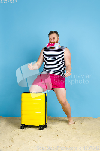 Image of Happy young man resting on blue studio background