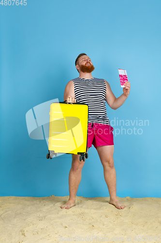 Image of Happy young man resting on blue studio background