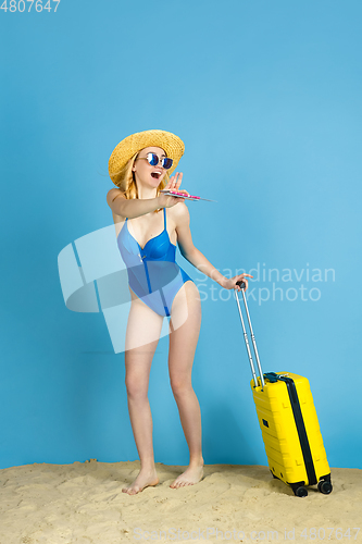 Image of Happy young woman resting on blue studio background