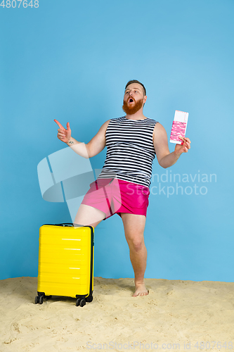 Image of Happy young man resting on blue studio background