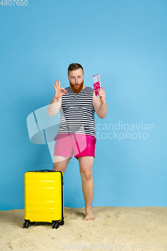 Image of Happy young man resting on blue studio background