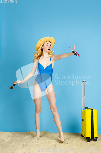 Image of Happy young woman resting on blue studio background