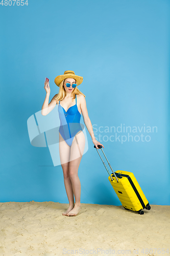 Image of Happy young woman resting on blue studio background
