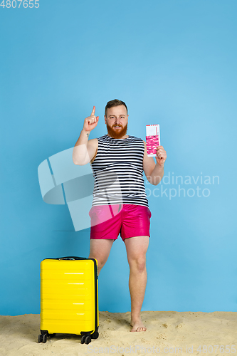 Image of Happy young man resting on blue studio background