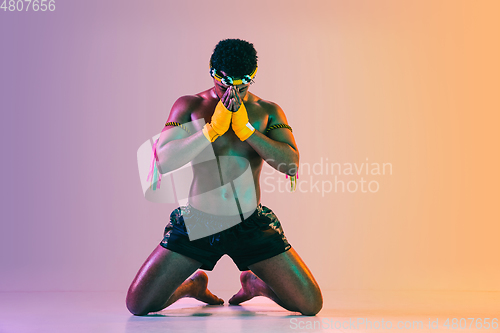 Image of Muay thai. Young man exercising thai boxing on gradient background