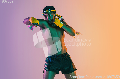 Image of Muay thai. Young man exercising thai boxing on gradient background