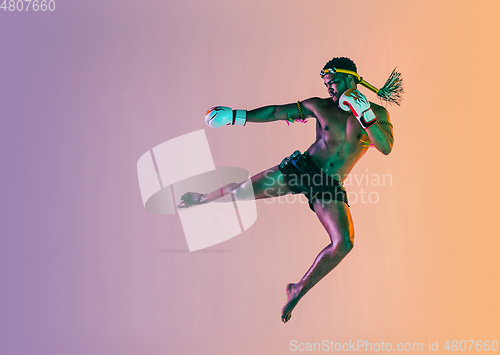 Image of Muay thai. Young man exercising thai boxing on gradient background