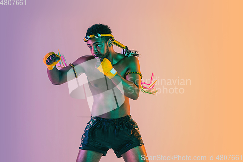 Image of Muay thai. Young man exercising thai boxing on gradient background