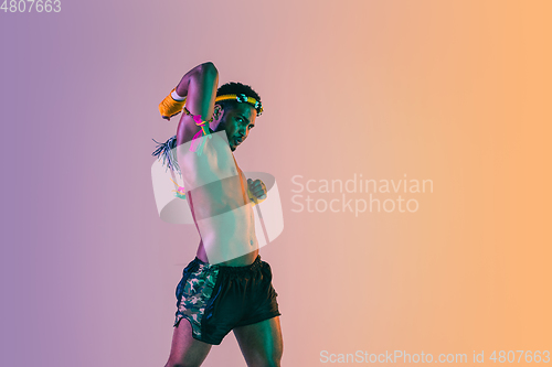 Image of Muay thai. Young man exercising thai boxing on gradient background