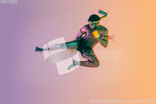 Image of Muay thai. Young man exercising thai boxing on gradient background