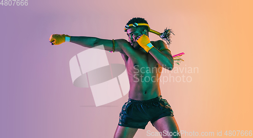 Image of Muay thai. Young man exercising thai boxing on gradient background