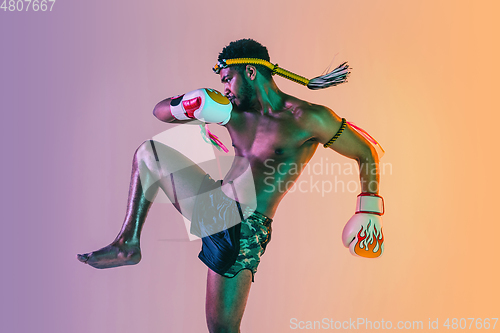 Image of Muay thai. Young man exercising thai boxing on gradient background