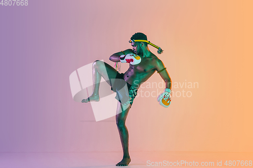 Image of Muay thai. Young man exercising thai boxing on gradient background