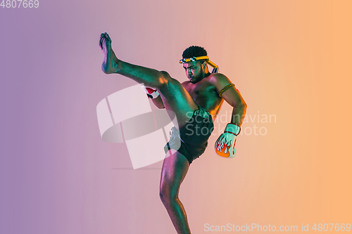 Image of Muay thai. Young man exercising thai boxing on gradient background