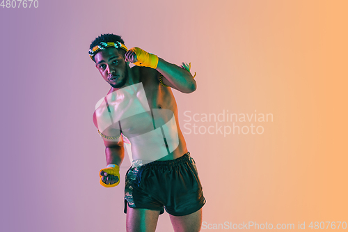 Image of Muay thai. Young man exercising thai boxing on gradient background