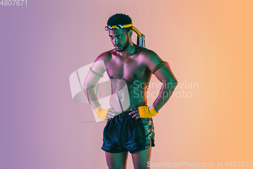 Image of Muay thai. Young man exercising thai boxing on gradient background