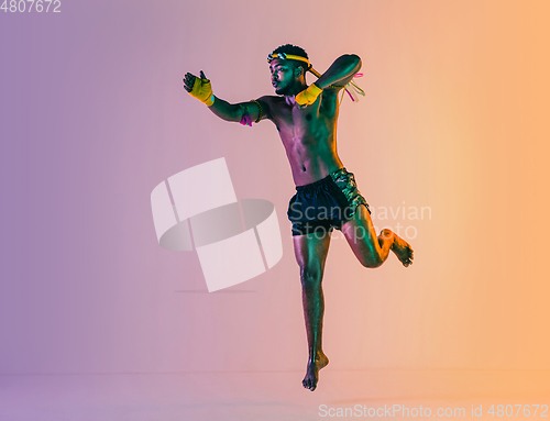 Image of Muay thai. Young man exercising thai boxing on gradient background