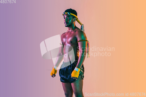 Image of Muay thai. Young man exercising thai boxing on gradient background